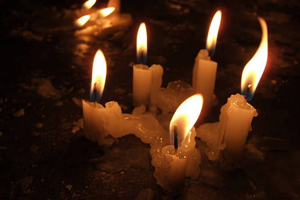 Group of five lit candles in a dark environment stock photo
