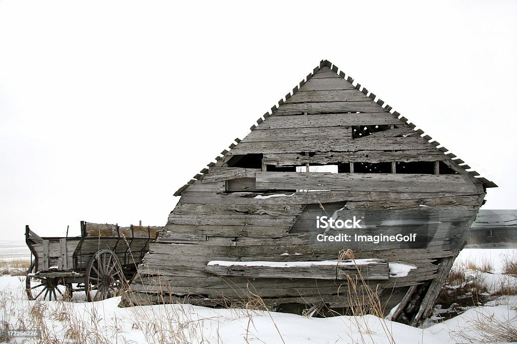 Ancient Cart and Barn A wooden cart and old barn abandoned on the plains. Farm Stock Photo