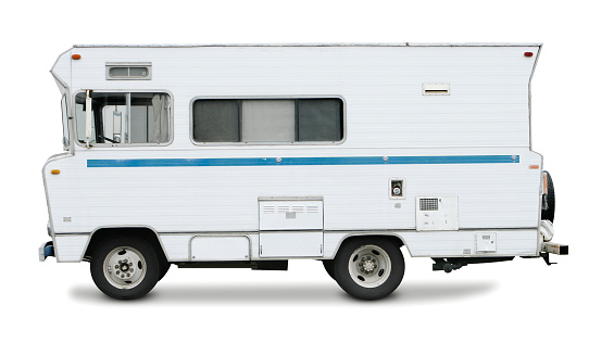 An old motorhome from the 1970's isolated on a white background. It sits at a profile to the camera.