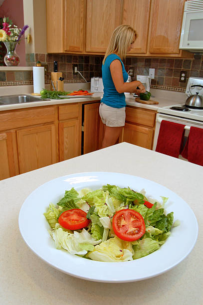 Jeune femme prépare salade dans la cuisine - Photo