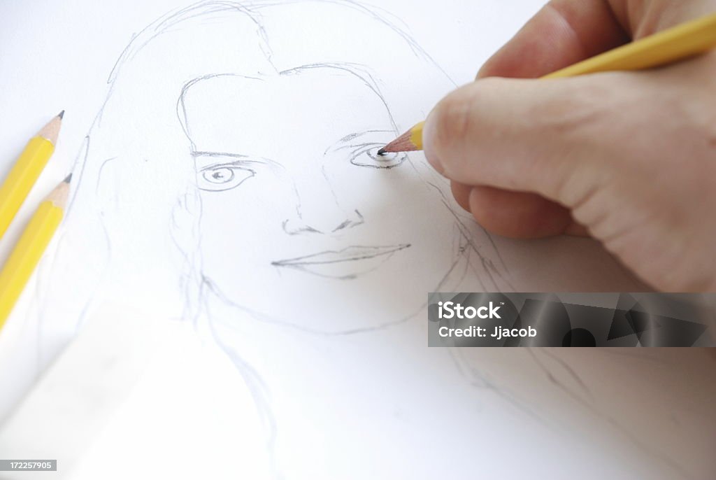 Draw a sketch A hand is drawing a portrait. Human Face Stock Photo