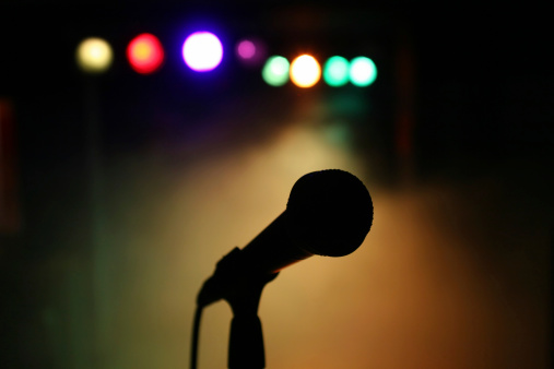 Silhouette of a microphone on stage in front of colorful reflectors