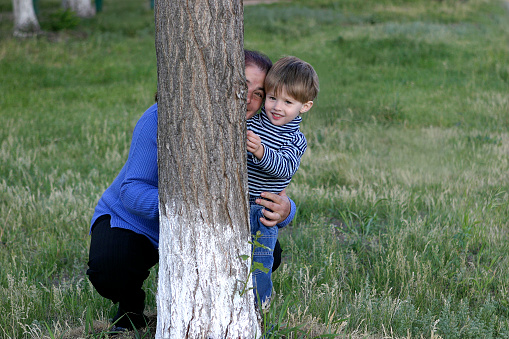 The grandmother with the grandson are hidden behind a tree.