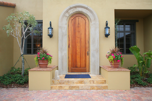 Front door of a home with stone steps, flower pots, and brick entry.