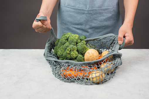 Mesh bag with vegetables, shopping grocery, healthy food ingredients, potato, broccoli and carrots, zero waste