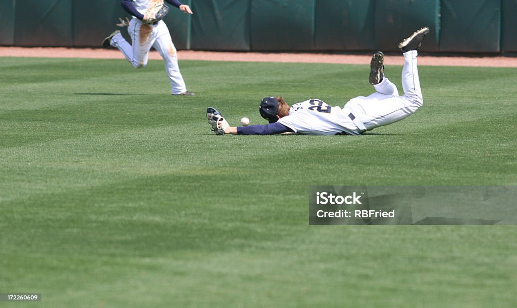 Man diving and missing the catch in baseball an outfielder diving and missing a ball Falling Stock Photo