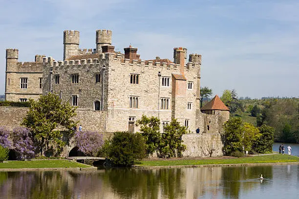 Photo of Leeds Castle, surrounded by trees and a clear body of water