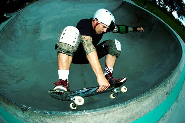 Male skateboarder performing a frontside air at a skateboard park.  Cross-processed fish-eye image.