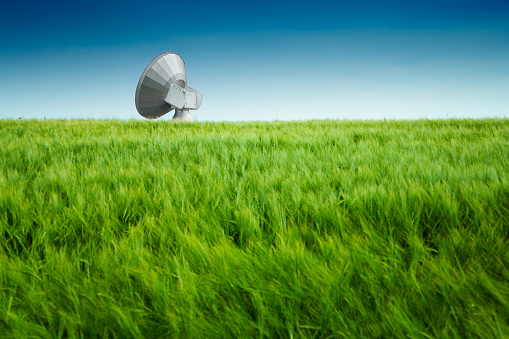 Telecommunication antenna for contacting satellites in the middle of a field.