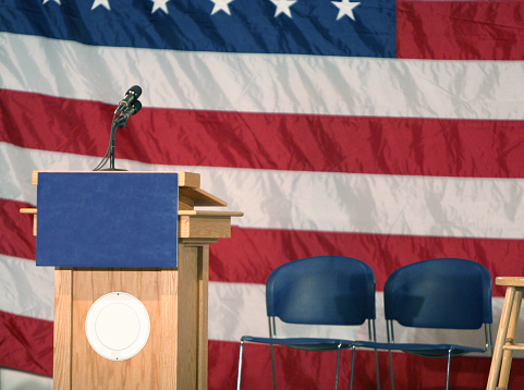 A podium sits in front of an American flag