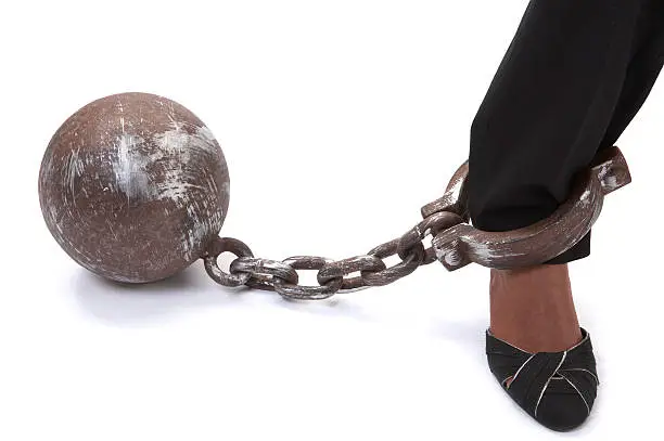 A businesswoman's foot chained to her work via a ball and chain. Shot in Adobe RGB with Canon 5D.