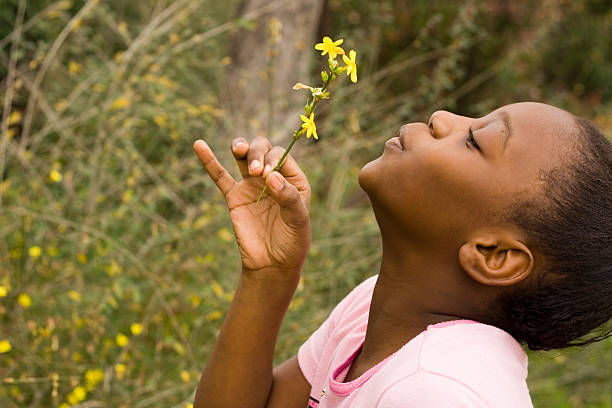 Young black girl blowing on yellow feather
