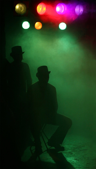 Silhouette of two men wearing hats at music concert