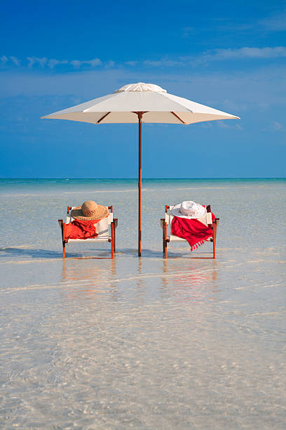 sillas y sombrilla, sombreros y sarongs en una playa de florida - outdoor chair beach chair sarong fotografías e imágenes de stock