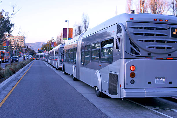 Rapid Transit Buses accordion bus articulated bendy Line of modern clean burning gas rapid transit buses at depot on busy street to take home riders from work; accordion bus, articulated bus woodland hills los angeles stock pictures, royalty-free photos & images