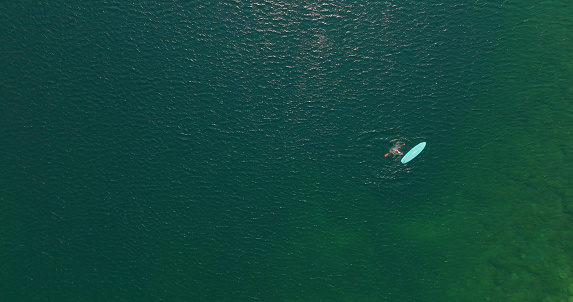 Aerial view of stand up paddle boarder (SUP) enjoys tranquil moments on lake
