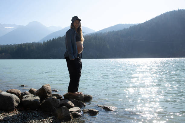 mujer joven se relaja en la orilla del lago por la mañana - stone wellbeing zen like blue fotografías e imágenes de stock