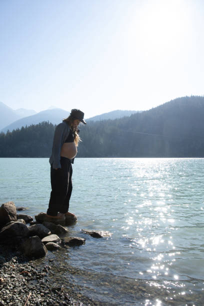 mujer joven se relaja en la orilla del lago por la mañana - stone wellbeing zen like blue fotografías e imágenes de stock