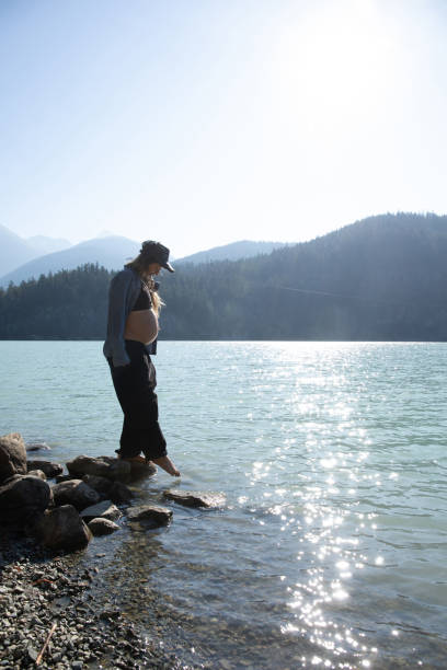 mujer joven se relaja en la orilla del lago por la mañana - stone wellbeing zen like blue fotografías e imágenes de stock