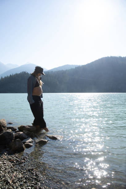 mujer joven se relaja en la orilla del lago por la mañana - stone wellbeing zen like blue fotografías e imágenes de stock