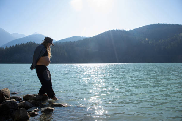 mulher nova relaxa à beira do lago pela manhã - stone wellbeing zen like blue - fotografias e filmes do acervo