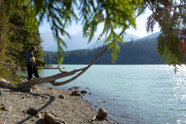 mujer joven se balancea y camina a lo largo del tronco, a la orilla del lago - stone wellbeing zen like blue fotografías e imágenes de stock