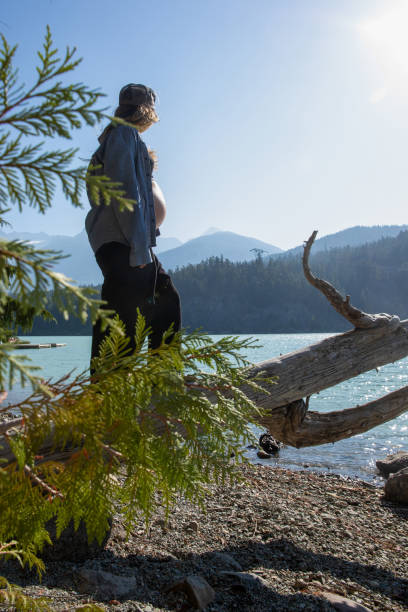 jovem se equilibra e caminha ao longo de tronco, à beira do lago - stone wellbeing zen like blue - fotografias e filmes do acervo