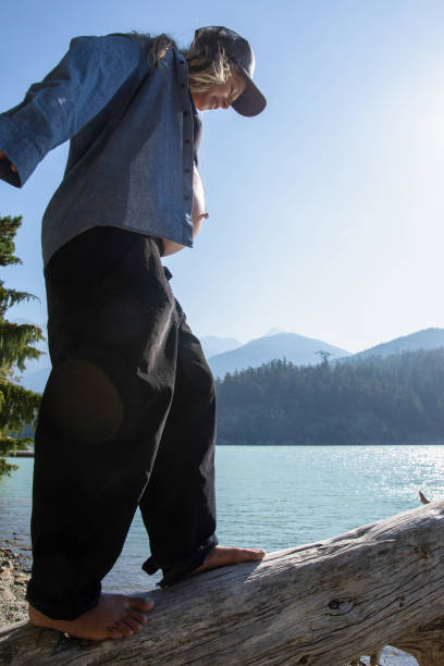 jovem se equilibra e caminha ao longo de tronco, à beira do lago - stone wellbeing zen like blue - fotografias e filmes do acervo