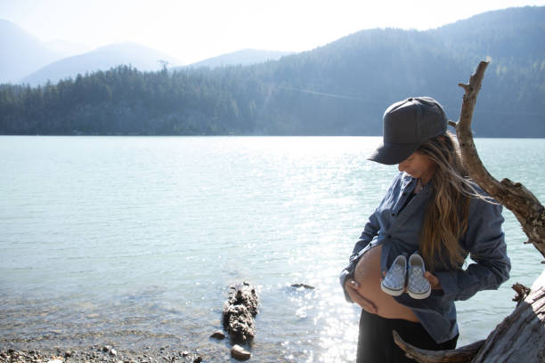 mujer joven se balancea y camina a lo largo del tronco, a la orilla del lago - stone wellbeing zen like blue fotografías e imágenes de stock