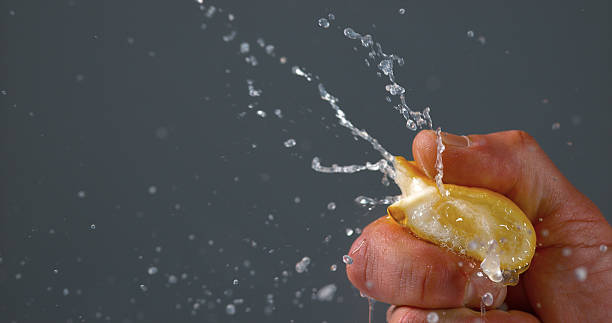 istock Hand of Man Squeezing Lemon, citrus limonum against Black Background 1722662799