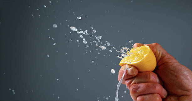 istock Hand of Man Squeezing Lemon, citrus limonum against Black Background 1722662851
