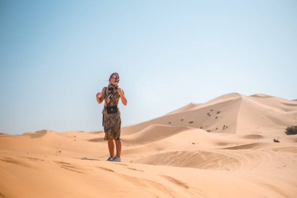 Young woman walks across sand dune