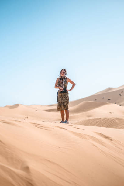 Young woman walks across sand dune