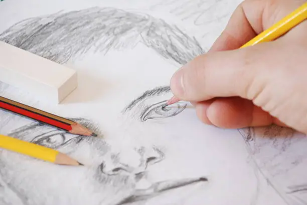 A hand is drawing a portrait.