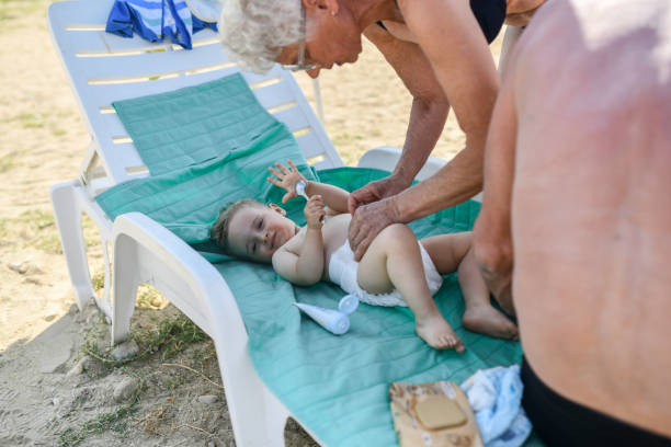 해변에서 아기 손자의 더러워진 기저귀를 제거하는 할머니 - grandson water waterfront portrait 뉴스 사진 이미지