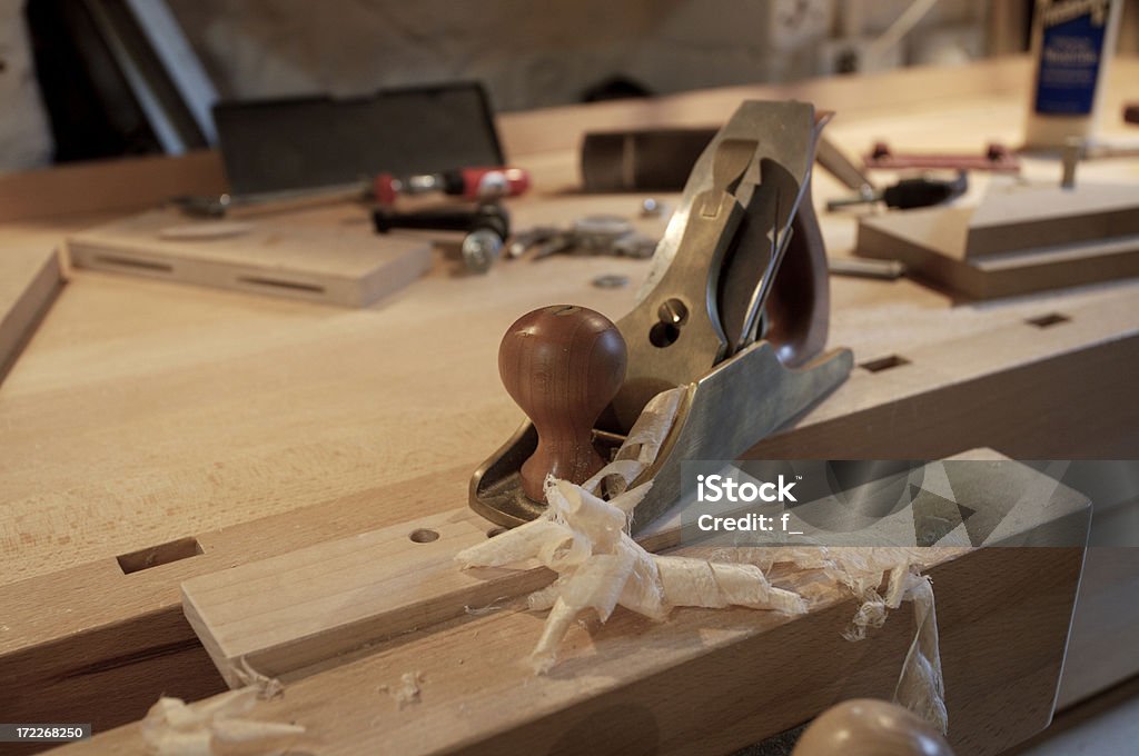 Bronze smoothing plane with wood shavings A bronze smoothing plane with wood shavings freshly cut from a piece of maple hardwood. Customized Stock Photo