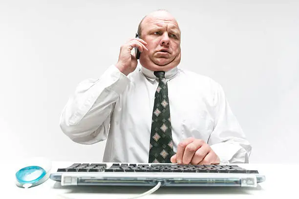 Wannabe fatcat business man talking on the phone in front of computer keyboard