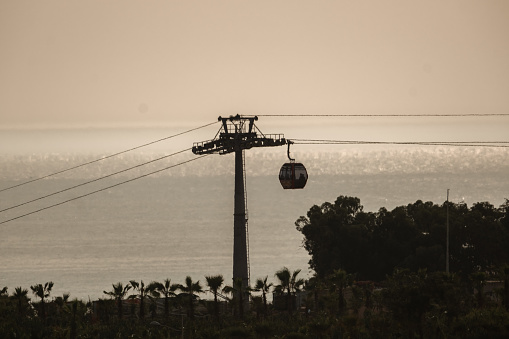 The gondola moves along a cable above the ocean at dusk