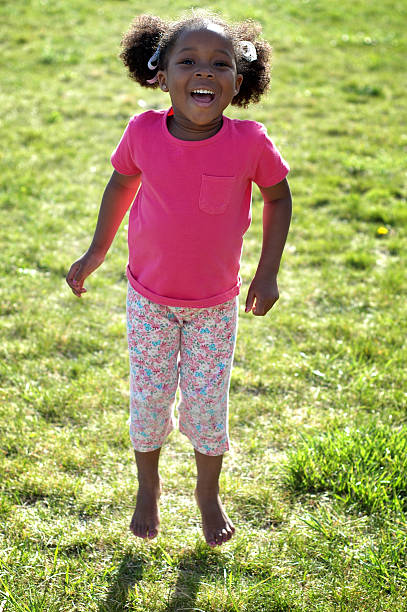 feliz niña de salto y riendo al aire libre - child dancing preschooler outdoors fotografías e imágenes de stock