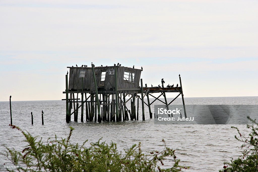 Cozy Cabin at the Shore This is the shell of a building left after storms and no repair.  At one time it was a fishing cabin with a dock leading out to it. Architectural Feature Stock Photo