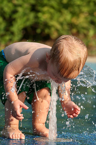 toddler splashed by water fountain in summer stock photo