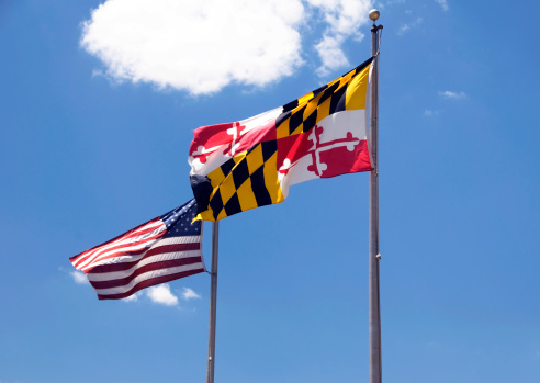 a Maryland flag and a US flag blowing in the wind