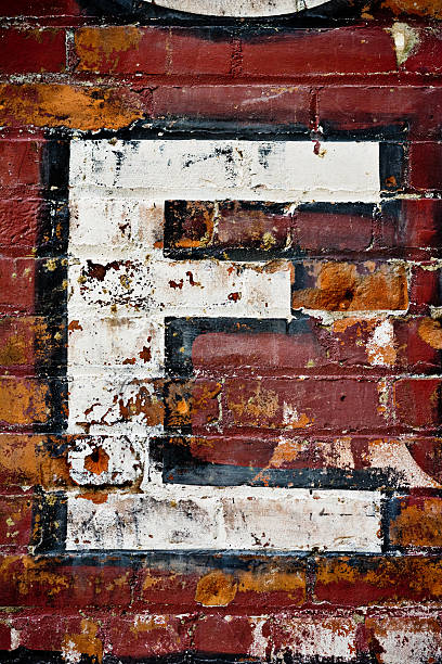 letra e en pared de ladrillos - alphabet brick brick wall dirty fotografías e imágenes de stock