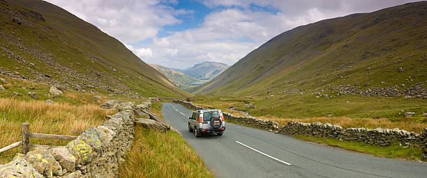 SUV on mountain pass "Silver 4x4 sports utility vehicle crossing the dramatic Kirkstone Pass from Windemere to Ullswater in the beautiful English Lake District, Cumbria, UK. Adobe RGB 1998 color profile." grass shoulder stock pictures, royalty-free photos & images