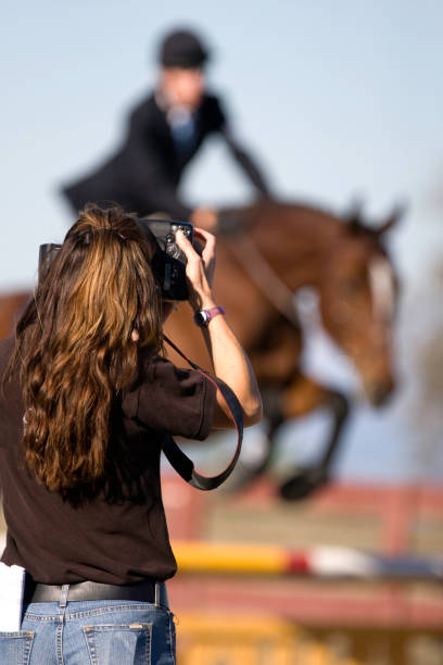 Equestrian Photographer a sports photographer in action with a horse in the background. great action shot. sports photography stock pictures, royalty-free photos & images