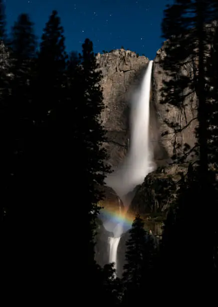 A rare lunar rainbow forms in the mid-summer across Yosemite Falls. The sufficiently-bright light supplied by the full moon hits the mist-filled air as the waterfall thunders with a heavy flow after a very wet winter.