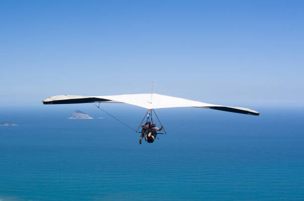 Silhouette of hang glider against blue sky with thunderclouds. Copy space.