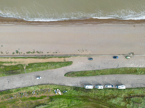 Drone top down view of parked up motor homes seen near the shoreline of the Suffolk coast in the UK.