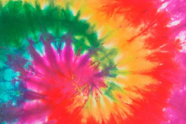 Psychedelic Tie Dye, a 1960s Style Symbol of Peace Background Colorful tie dye fabric with spiral circle pattern in rainbow colors. The free-form pattern is associated with 1960s and 1970s fashion style and a symbol of peace and the peace movement of that era. The multi-colored array of vibrant color was the essence of cool, groovy, psychedelic trends. psychedelia stock pictures, royalty-free photos & images