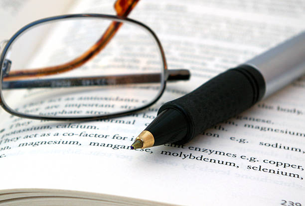 Pen and spectacles on scientific paper stock photo